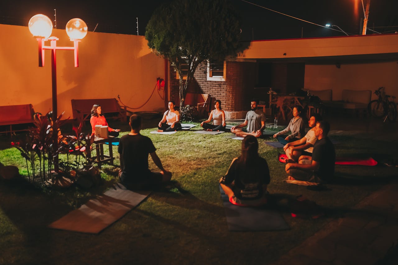 A group of adults practicing yoga outdoors at night, fostering relaxation and wellness.