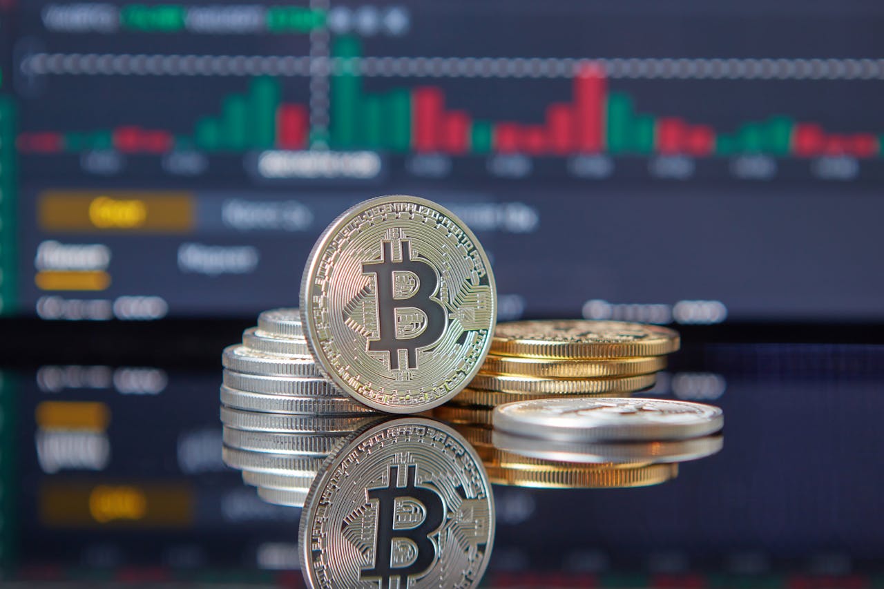 Close-up of Bitcoin coins on reflective surface with financial trading chart, symbolizing cryptocurrency market dynamics.