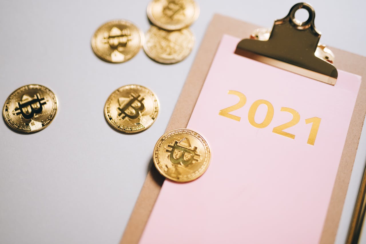 Golden bitcoins scattered around a 2021 clipboard, symbolizing financial planning.